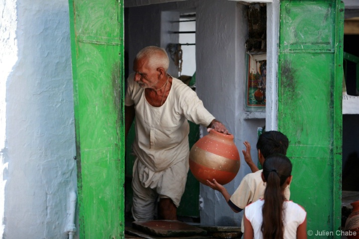 Old man giving water to kids