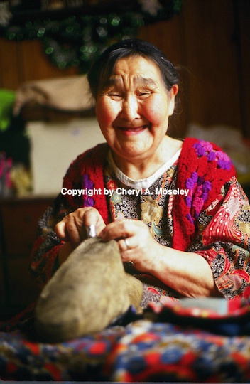 Eskimo Woman sewing animal skin into garment