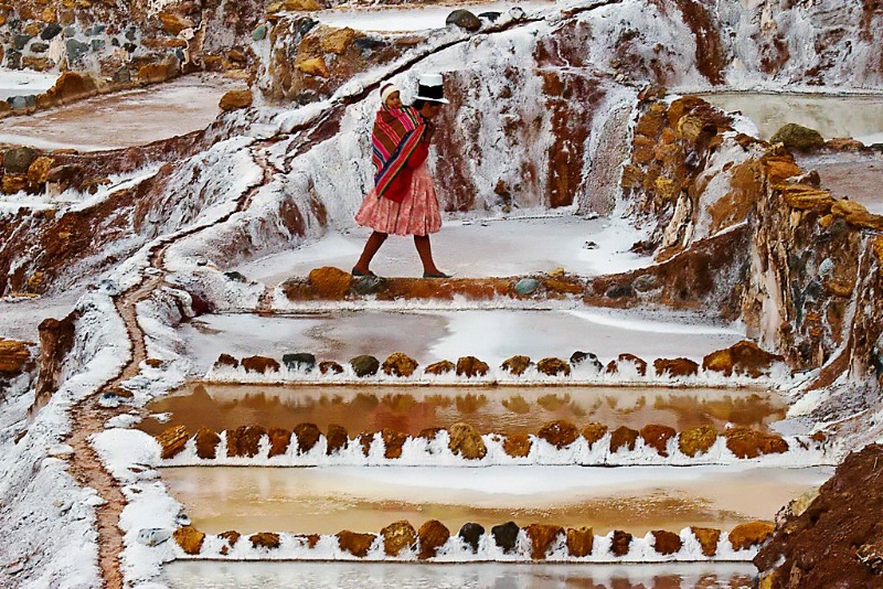 Peruvian woman and child walking along salt pools