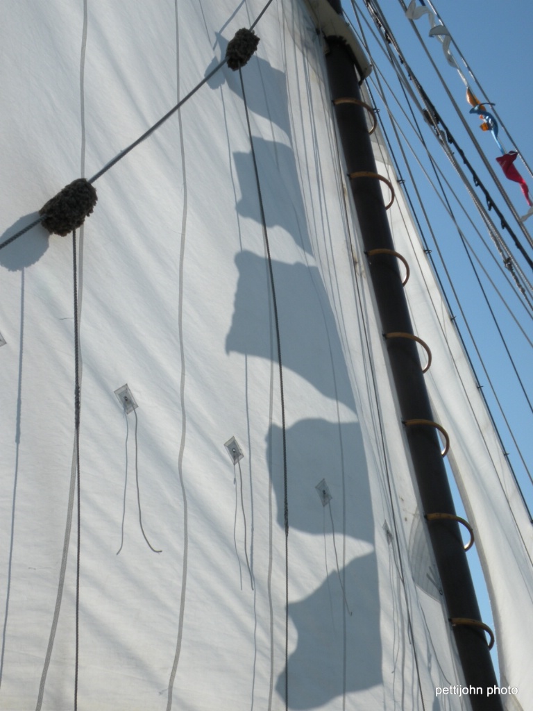 Shadow of schooner flags on white sails