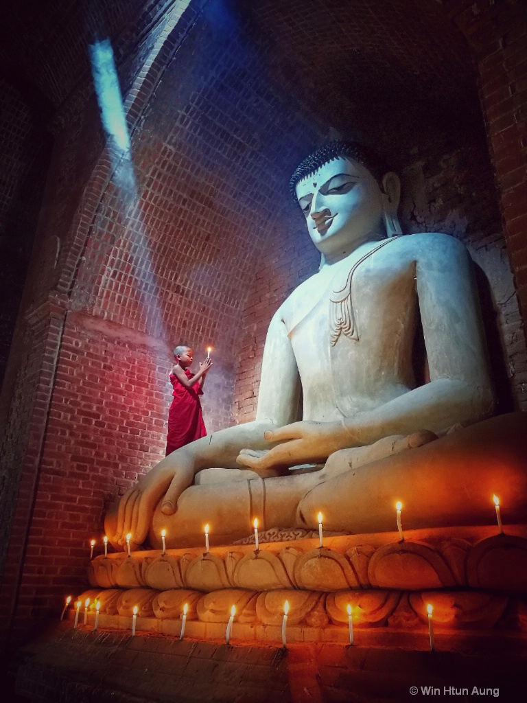 Novice monk praying with candle