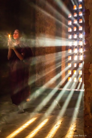 A novice praying with candle in Bagan